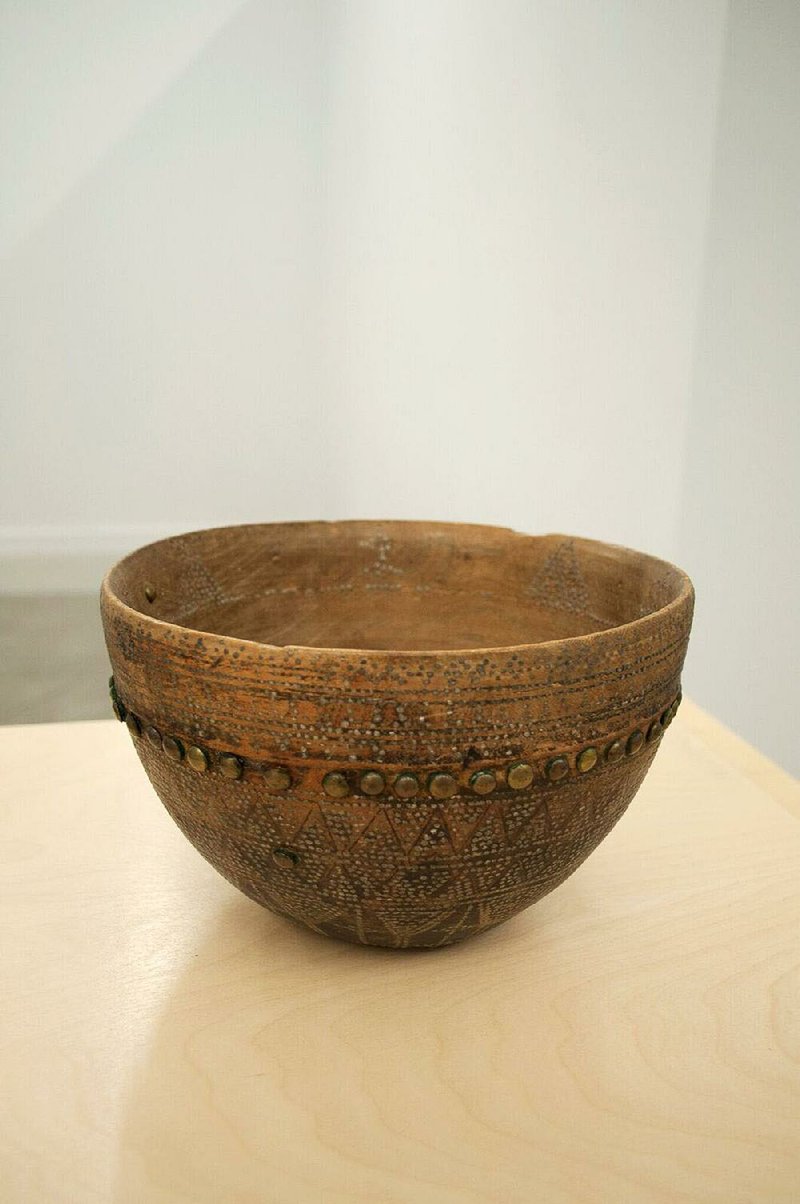 A camel milk bowl made of wood, silver and brass is on display at the University of Arkansas at Little Rock. 
