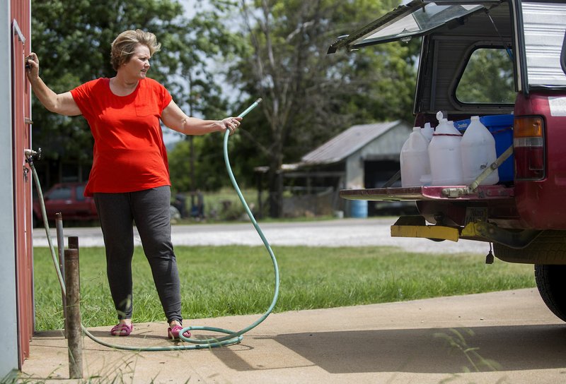 Marilyn La Combe drops a quarter into the coin-operated water station Thursday outside the Evansville Volunteer Fire Department. La Combe hauls jugs of water to her home every day. 
