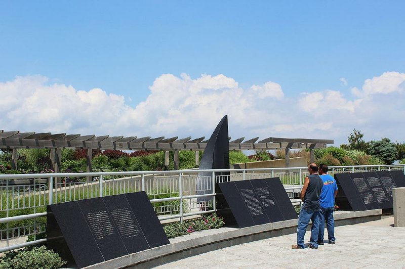 Two men look at part of the TWA Flight 800 Memorial in Smith Point County Park in Shirley, N.Y., in June.