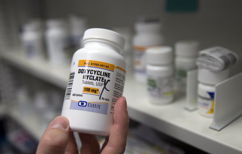 In this Friday, July 8, 2016, photo, pharmacist Clint Hopkins, owner of Pucci's Pharmacy, displays a bottle of the antibiotic doxycycline hyclate, in Sacramento, Calif. 