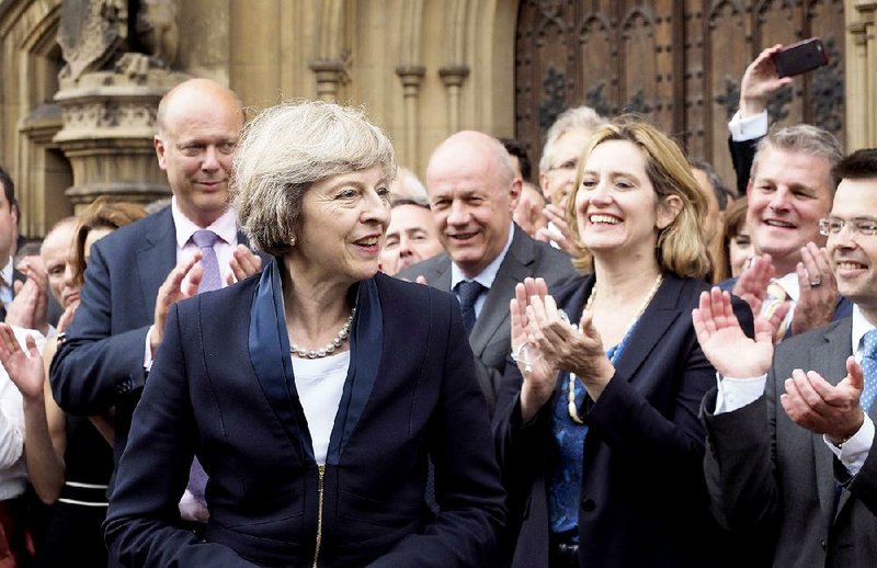 Britain’s Theresa May is applauded Monday by Conservative Party members of Parliament outside the Houses of Parliament in London.