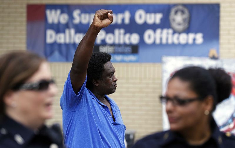 A protester stands behind Dallas police officers at their headquarters Monday in Dallas.