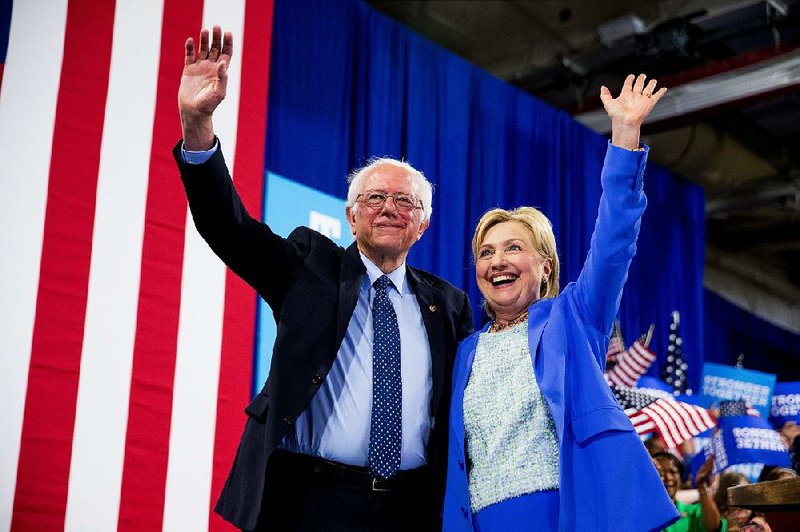 Bernie Sanders stands with Hillary Clinton at a rally Tuesday in Portsmouth, N.H. In endorsing Clinton, Sanders said that the election “must be about bringing our people together, not dividing us up.” 
