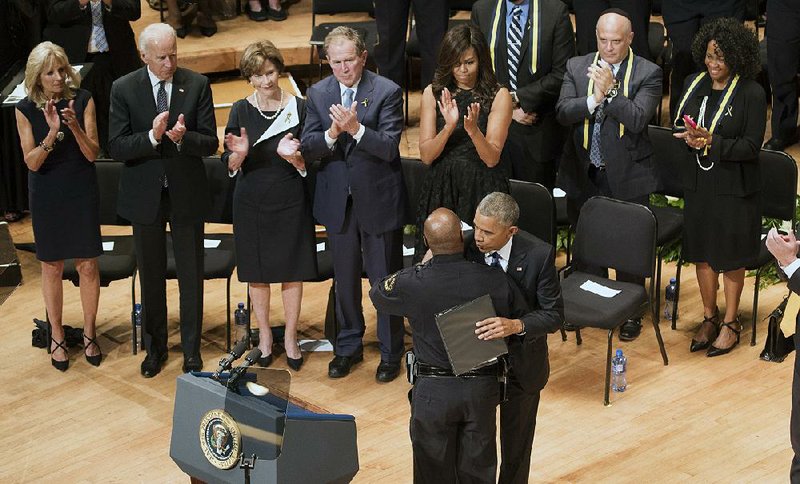 President Barack Obama embraces Dallas Police Chief David Brown during a memorial service Tuesday in Dallas for five slain police officers. Vice President Joe Biden (background, from left), Laura Bush, former President George W. Bush and Michelle Obama applaud the moment. 