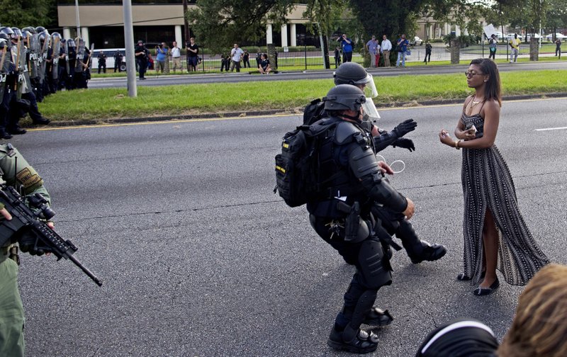  In this Saturday, July 9, 2016 file photo, A protester is grabbed by police officers in riot gear after she refused to leave the motor way in front of the the Baton Rouge Police Department Headquarters in Baton Rouge, La. 