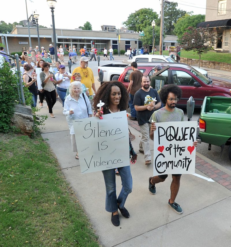 Jasmine Matthews (left) and Cory Perry carry signs Wednesday as they join community members marching up North Block Avenue on their way to the Fayetteville Police Department during a vigil and candlelight walk in memory of Sandra Bland and others as part of the Black Lives Matter movement. Wednesday was the one-year anniversary of Bland’s death in a Texas jail.