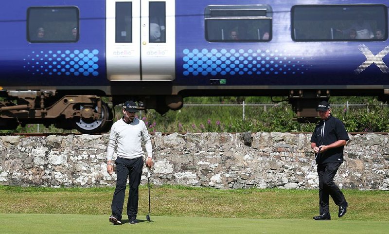 Justin Leonard (left) and Todd Hamilton eye their putts as a passenger train passes a few feet from the 11th green at the British Open on Thursday.