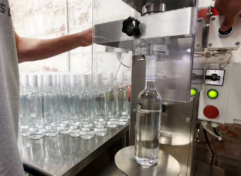 Chase Ming seals a bottle of vodka at the Cathead Distillery in Jackson, Miss., in this file photo. The number of Americans seeking unemployment benefi ts last week was unchanged at 254,000 and U.S. wholesale prices rose more than forecast in June, reports released Thursday said.