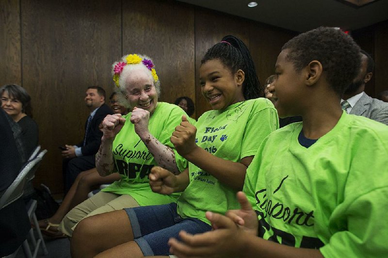 Longtime volunteer Darlinea Wadood (left) celebrates with grandchildren Janiya Gabriell Stephenson (center) and James Garfi eld Stephenson IV after the Arkansas Board of Education approved Little Rock Preparatory Academy’s charter middle school’s move to a new location.