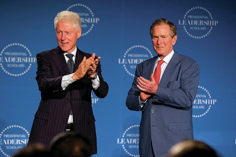 FILE — Former Presidents Bill Clinton (left) and George W. Bush celebrate with the Presidential Leadership Scholars during their graduation at Little Rock Central High School in 2016.