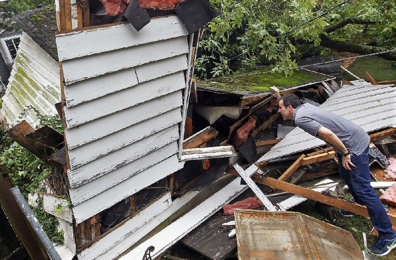 Wil Smith examines the detached garage at his home on North Garfield Road in Little Rock after the structure was crushed by a tree during Thursday night’s storms.