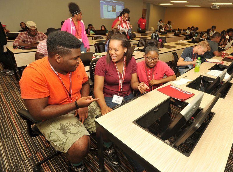 Jacoby Hurst (from left), a high school junior from Marion Talia West, a junior from Fayetteville, and Justice Galaspie, a junior from Eldorado, work on their project Wednesday in Fayetteville as they participate in the Fleischer Scholars program at the University of Arkansas. The program is part of an effort by Arizona financier Morton Fleischer to bring business opportunities to underserved populations. Students, currently in high school, are visiting the campus for the weeklong program.