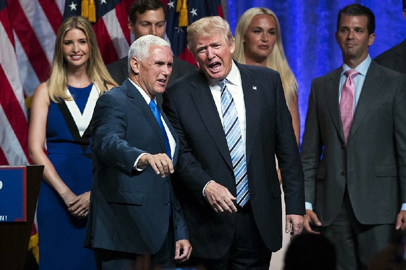 Mike Pence talks with Donald Trump after he was introduced Saturday in New York as Trump’s presidential running mate. Behind them are members of Trump’s family.