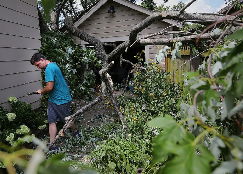 Eric Worsham helps remove limbs from his neighbor’s house Saturday along Longwood Road in Cammack Village. A tree service contracted with Cammack Village to help residents dispose of debris from last week’s storms.
