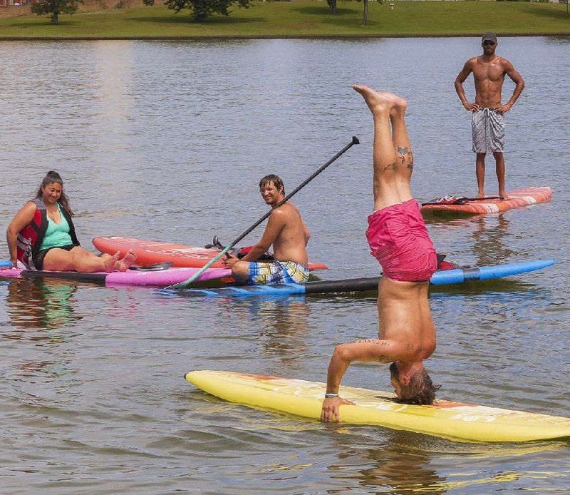 T.J. Griffith’s stand-up paddleboarding students work out together on Lake Hamilton while earning physical education credit with National Park College in Hot Springs.