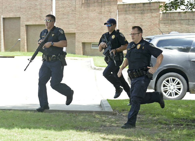 Baton Rouge police officers run from the emergency room ramp as a man is taken into custody after a gun was found in his vehicle near the entrance of Our Lady of the Lake Regional Medical Center on Sunday in Baton Rouge, where wounded officers were taken.