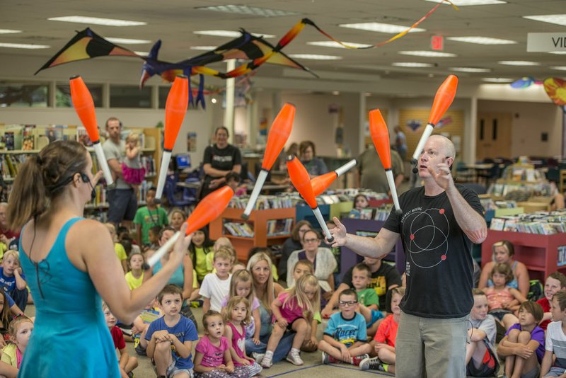 Galen Harp and Ellen Winters, with the Institute of Jugglology, perform Thursday at the Springdale Public Library. The group performed as part of the library’s summer reading program.