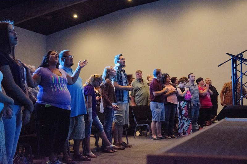 Members of The Gathering Place raise their hands during worship Sunday morning in Searcy.