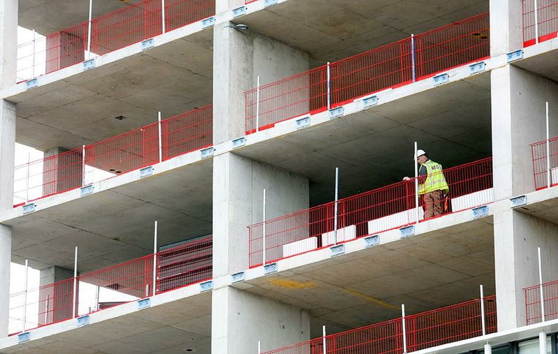 A construction worker looks out from a residential apartment building this month in the Stratford district of London.