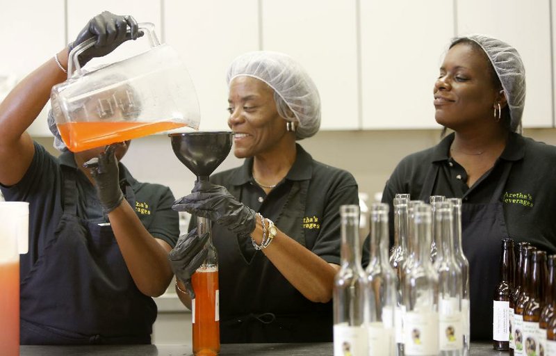 Jacinda Jones (far right) watches while Janee Jones-Lankford and Eartha Daniel are filmed by the production crew of P. Allen Smith as they bottle Strawberry Lemonade with Basil — one of three drinks in the Aretha’s Beverages product line — at the University of Arkansas Institute of Food Science and Engineering Food Innovation Center in Fayetteville.