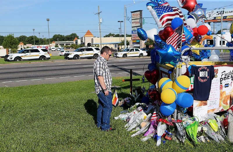 Matthew Ward, an employee with the Baton Rouge sheriff’s office who knew slain Deputy Brad Garafola, visits a makeshift memorial Tuesday for the officers who were killed and wounded in Sunday’s shooting in Baton Rouge.