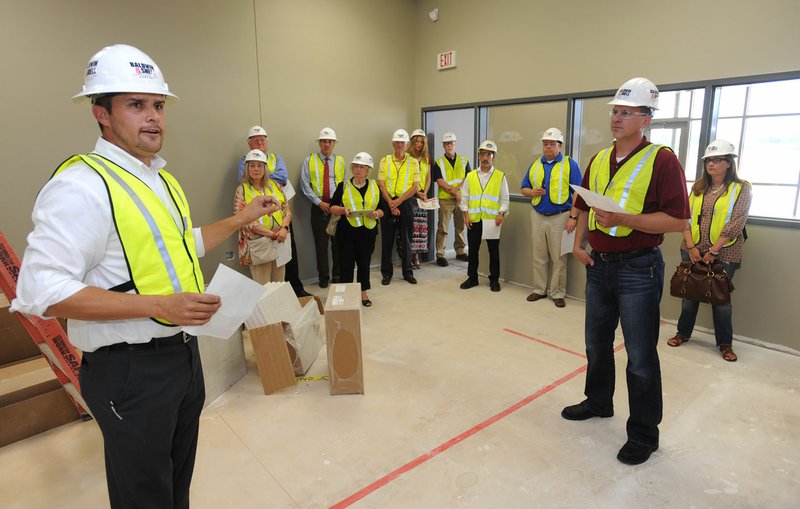 Joe Rollins (left), principal of the Don Tyson School of Innovation, speaks Tuesday with members of the School Board during a tour of the school which is under construction in Springdale. Members of the board toured the school and Childers Knapp Elementary School, both of which are expected to open in the fall. Visit nwadg.com/photos to see more photographs from the tours.
