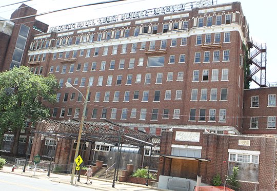 The Sentinel-Record/Richard Rasmussen STILL STANDING: An unidentified pedestrian walks past the Majestic Hotel Tuesday afternoon, shortly after the organizer of an online petition to save the hotel filed an injunction in an attempt to stop demolition work that began last week.