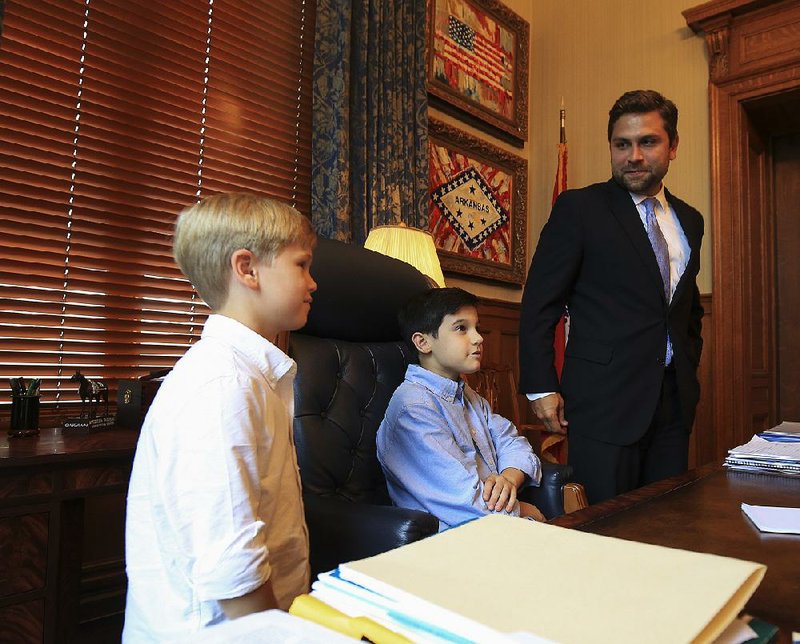 Senate President Pro Tempore Jonathan Dismang takes time Wednesday to give his sons Sawyer (left), 6, and Cade, 12, a feel for the governor’s office.