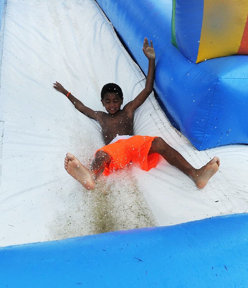 Odie Williams III, 8, cools off Wednesday on a water slide at Walker Park in Fayetteville. Temperatures in Northwest Arkansas have remained in the low 90s or lower, but much of the state is under a heat advisory through Friday.