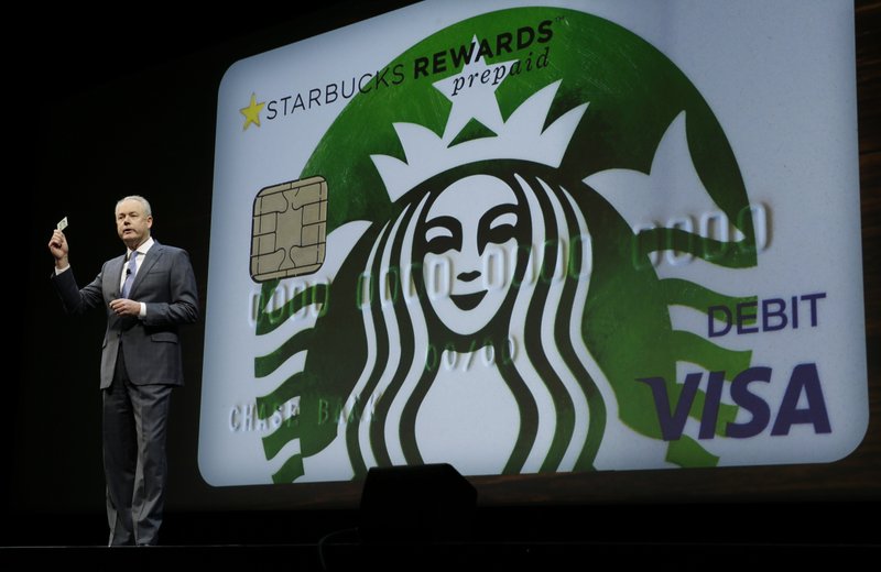In this Wednesday, March 23, 2016, file photo, Kevin Johnson, president and chief operating officer of Starbucks Corp., holds up one of the coffee company's new prepaid Visa debit cards, at the coffee company's annual shareholders meeting in Seattle. 