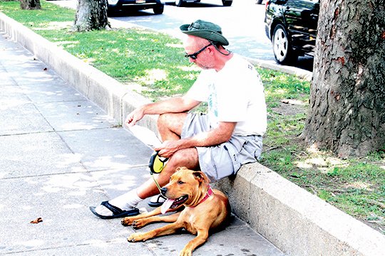 The Sentinel-Record/Colbie McCloud IN THE SHADE: Rick Marshall, of Texas, and his dog, Cooper, take a break from the heat in the shade on Bathhouse Row downtown Thursday while reading a brochure about Hot Springs. Temperatures are expected to reach into the upper 90s for the next several days with heat index values climbing into the triple digits.
