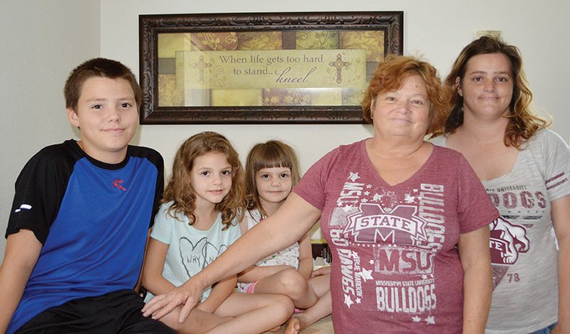 Melinda Davis, 58, second from right, stands with her daughter, Crystal Yeakley, right, and Yeakley’s three children, from left, Tyler, 11, Maddie, 6, and Autumn, 4, in their new home in Vilonia built by Christian Aid Ministries and the Vilonia Disaster Recovery Alliance. Davis and her husband, the late David Davis, bought the print on the wall after they survived the 2014 Vilonia tornado. David was killed in a car wreck four days before the one-year anniversary of the 2014 tornado.