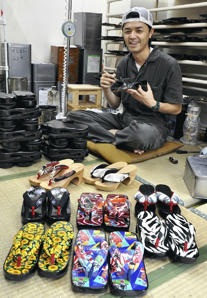 Masayuki Motono holds a geta sandal he made at his factory in Hita, Japan.