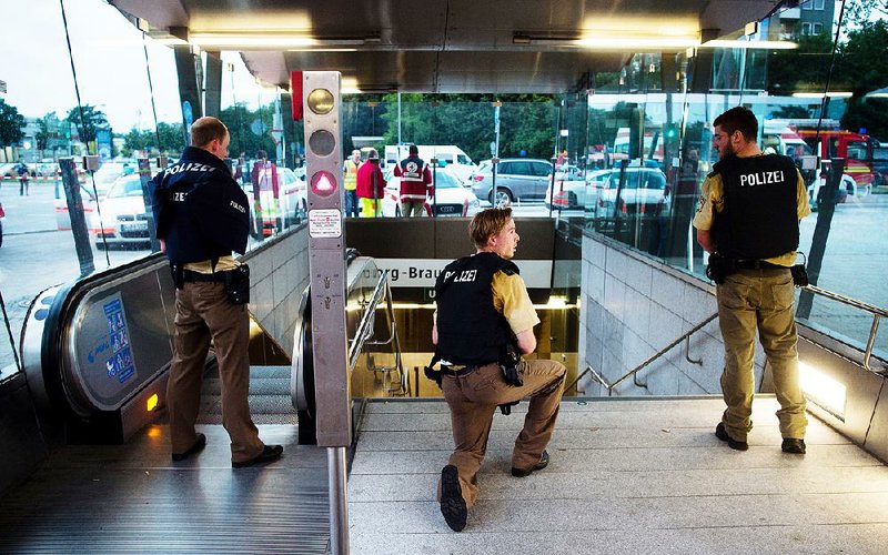 German police officers keep a lookout Friday at a subway station near a Munich shopping mall where a gunman opened fi re. The gunman’s whereabouts were not known until later in the evening.