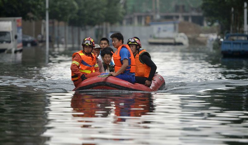 Rescuers use a raft Thursday to transport people along a fl ooded street in Shenyang in China’s northeastern Liaoning province.