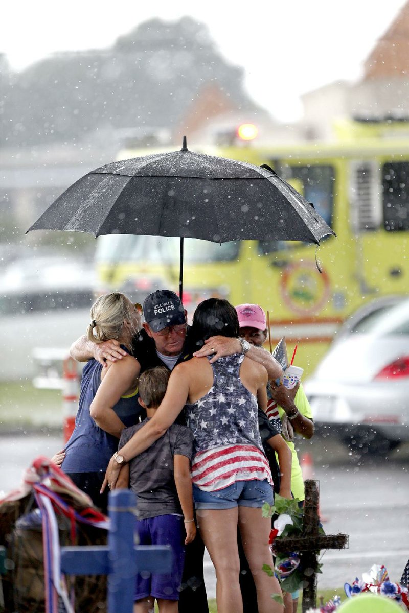 Robert Ossler, chaplain for the Millville, N.J., Police Department, hugs people Saturday at a makeshift memorial at the site where several police officers were killed last week in Baton Rouge.