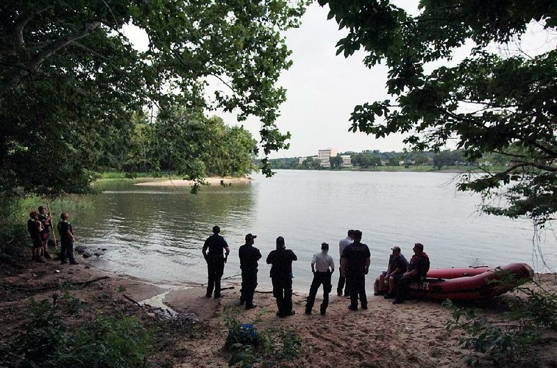 North Little Rock emergency services workers wait for lightning to pass and for Pulaski County divers to arrive Saturday during the rescue effort for a swimmer on the Arkansas River.