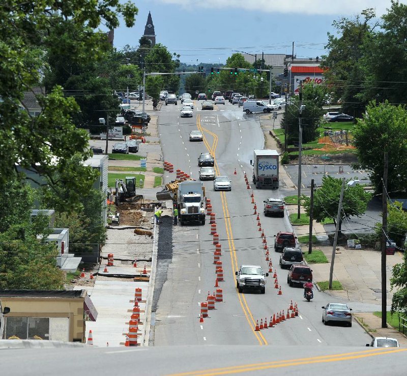 A construction crew works earlier this month on a project to widen the sidewalk on the east side of College Avenue in Fayetteville.