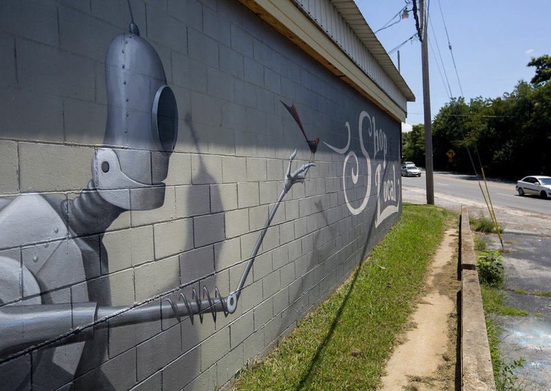 Traffic passes the Shop Local mural by artist Jason Jones on Friday on Archibald Yell Boulevard in Fayetteville.