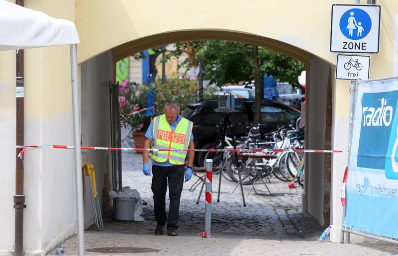 A member of the German police stands behind a police tape in Ansbach, Germany, Monday, July 25, 2016, near the site where a failed asylum-seeker from Syria blew himself up and wounded 15 people after being turned away from an open-air music festival in southern Germany. The man recorded a cell phone video of himself pledging allegiance to the Islamic State group before he tried to get into the outdoor concert with a bomb-laden backpack. (Karl-Josef Hildenbrand/dpa via AP)
