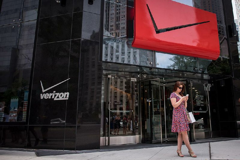 A pedestrian checks her phone outside a Verizon Communications Inc. store Monday in downtown Chicago. Verizon on Monday agreed to pay $4.83 billion to buy Yahoo Inc.’s Web assets.