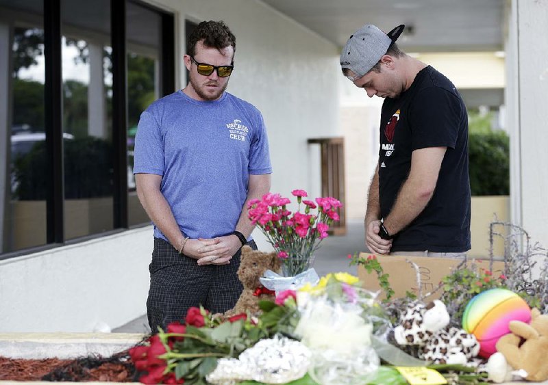 Dave Allen, 25, and Ryan Caviness, 26, pray Monday for the victims of a deadly shooting outside the Club Blu nightclub in Fort Myers, Fla.