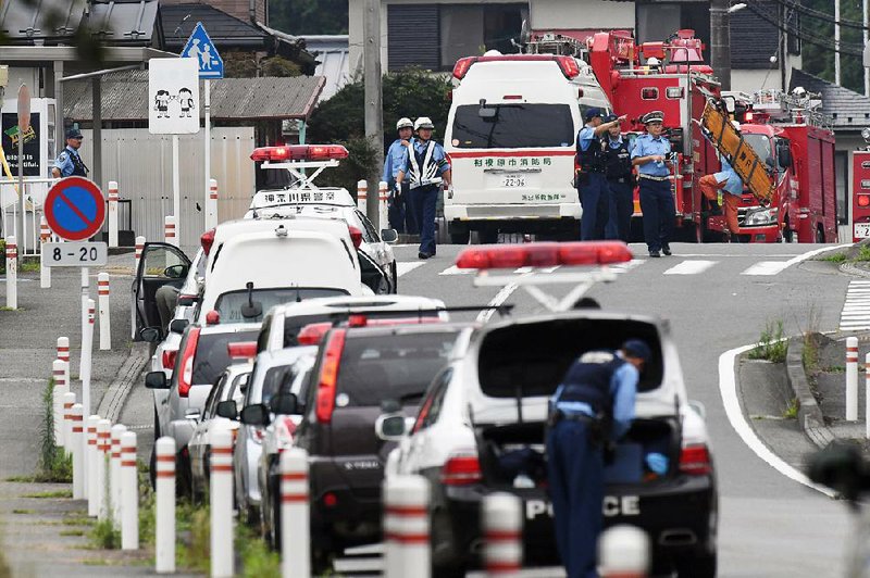 Police officers stand by early today with ambulances and fi retrucks near a facility for the handicapped where a number of people were killed and dozens injured in a knife attack in Sagamihara, outside Tokyo.