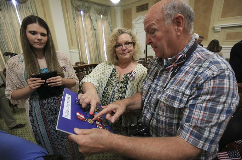 Family of Army veteran William Eugene Ballew, his granddaughter Jessy Ballew (left), daughter Julie Ballew Kersey and brother Max Ballew, look at medals awarded to the family Monday during a service at the state Capitol. William Ballew served in the Army during the Korean and Vietnam wars.