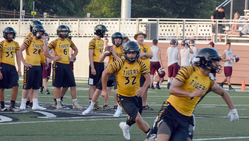 GRAHAM THOMAS ENTERPRISE-LEADER Prairie Grove coach Danny Abshoer looks on as senior quarterback Zeke Laird looks down the field while senior Reed Orr (32) and junior Anthony Johnson (1) run pass routes during a 7-on-7 game at Siloam Springs on July 11.