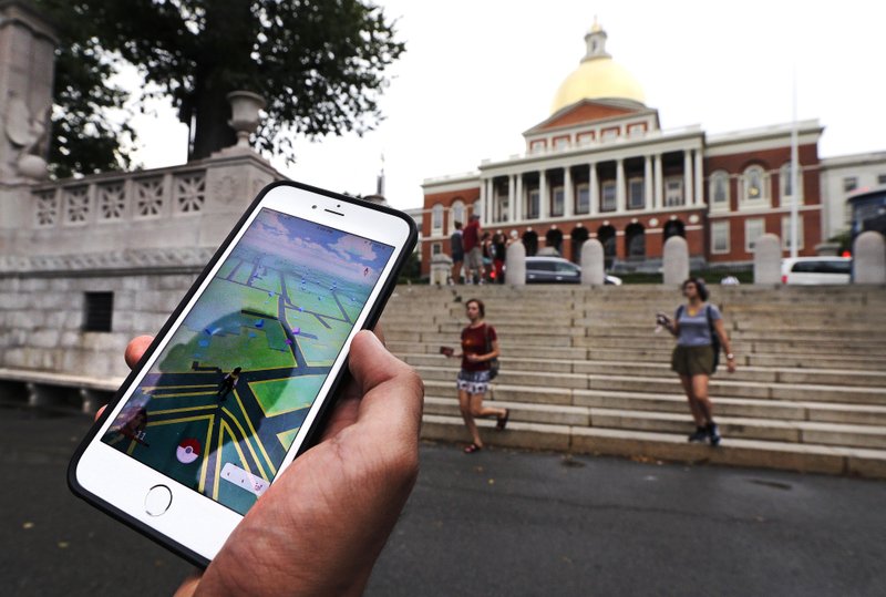 In this Monday, July 18, 2016, photo, a "Pokemon Go" player shows his mobile phone while walking through the Boston Common, outside the Massachusetts Statehouse in Boston. 