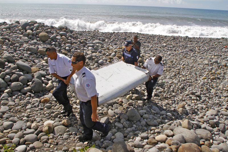 FILE - In this July 29, 2015, file photo, French police officers carry a piece of debris, the first trace of Malaysia Airlines Flight 370, in Saint-Andre, Reunion Island.