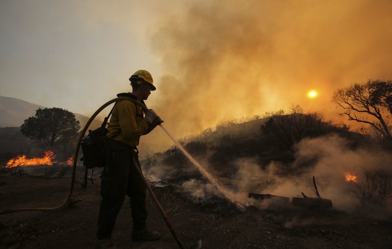 A firefighter battles a wildfire near Placenta Canyon Road in Santa Clarita, Calif., Sunday, July 24, 2016. Thousands of homes remained evacuated Sunday as two massive wildfires raged in tinder-dry California hills and canyons. 