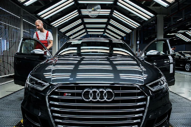 A worker conducts a quality-control check on an Audi S3 on Monday at a plant in Gyor, Hungary. A U.S. judge gave preliminary approval Tuesday to a plan to compensate consumers whose Volkswagen and Audi vehicles have engines designed to cheat emissions tests. 