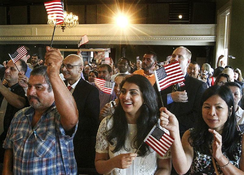 Alfonzo Lopez (from left), Summaiya Shah and Thu Huong Thi Phan wave American flags Tuesday during a naturalization ceremony at the Old State House Museum in Little Rock. 